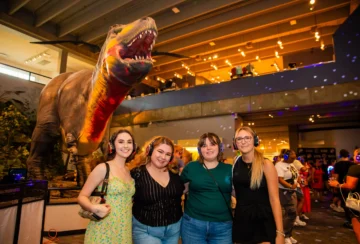 Four woman posing for a picture in front of the Science Center's animatronic Tyrannosaurus Rex.