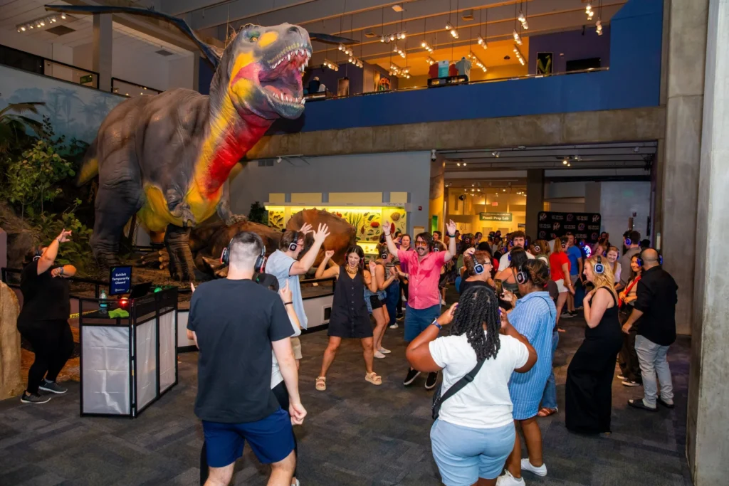 Guests at Science Center Up Late enjoy dancing underneath the watchful stare of the iconic T. rex.
