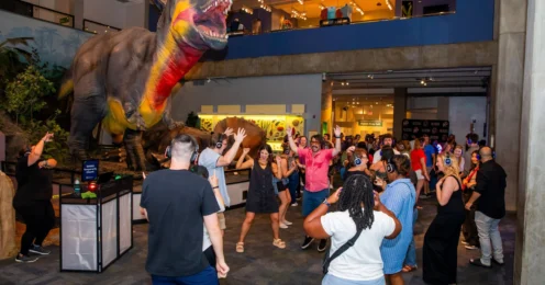 Guests at Science Center Up Late enjoy dancing underneath the watchful stare of the iconic T. rex.